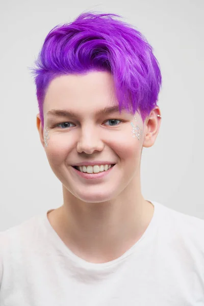 Portrait of a young attractive woman in a white T-shirt on a white background. Purple-colored short hair.