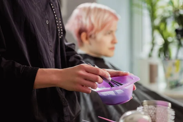 Cabeleireiro colorista amassa tinta para tingir o cabelo . — Fotografia de Stock