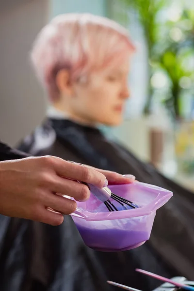 Cabeleireiro colorista amassa tinta para tingir o cabelo . — Fotografia de Stock