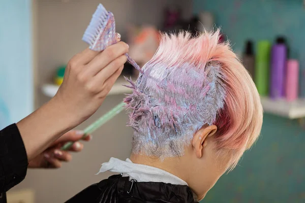 Cabeleireiro colorista tinge o cabelo de uma mulher para um cliente em cores diferentes . — Fotografia de Stock