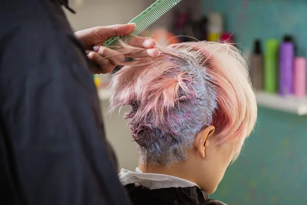 Coloriste coiffeur teint les cheveux d'une femme à un client en différentes couleurs . — Photo