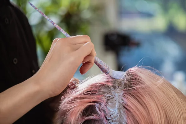 Coloriste coiffeur teint les cheveux d'une femme à un client en différentes couleurs . — Photo