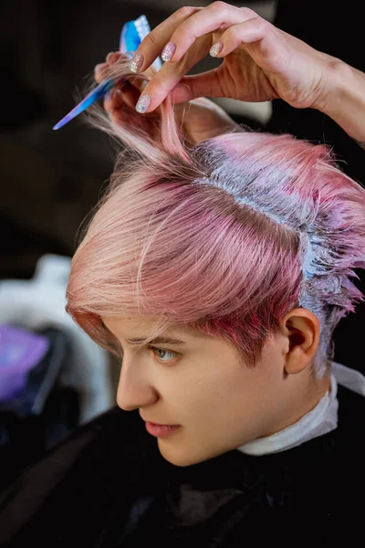 Cabeleireiro colorista tinge o cabelo de uma mulher para um cliente em cores diferentes . — Fotografia de Stock