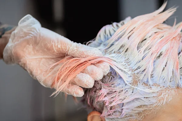 Cabeleireiro colorista tinge o cabelo de uma mulher para um cliente em cores diferentes . — Fotografia de Stock