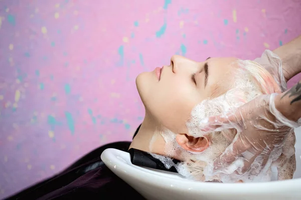 O cabeleireiro lava a cabeça de uma mulher para um cliente. Corante . — Fotografia de Stock