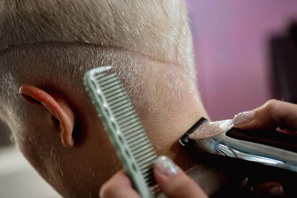 Hairdresser machine cuts woman client. A short haircut, shaved temple and a drawing on the hair. — Stock Photo, Image