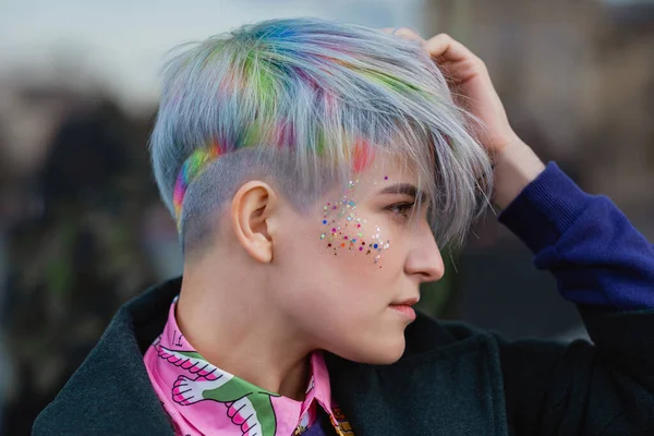 Portrait of a young beautiful woman in green coat with a short haircut and dyed hair. Grey main color and yellow, green, blue and red hair color. — Stock Photo, Image