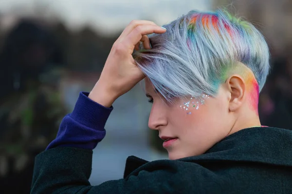 Retrato de una joven hermosa mujer en abrigo verde con un corte de pelo corto y cabello teñido. Color principal gris y color de pelo amarillo, verde, azul y rojo . —  Fotos de Stock