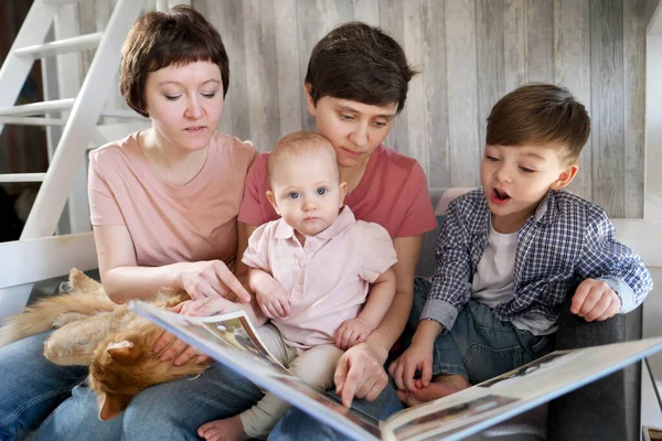 İki çocuğu, bir oğlu ve bir kızı olan lezbiyen bir eşcinsel aile evde vakit geçiriyor. Kanepeye oturup kitap okuyorlar. Evcil kedi onun yanında yatıyor..
