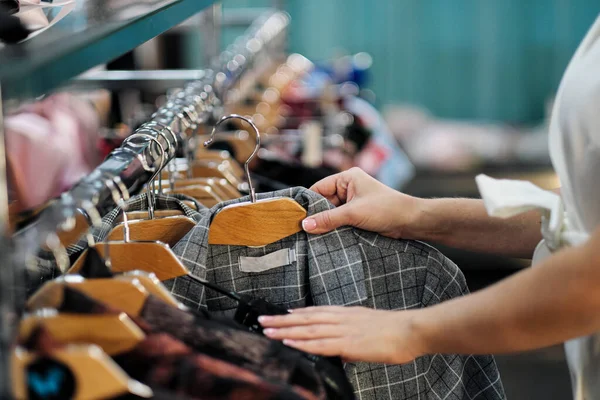 Close-up van de handen van een vrouw die kleding kiest aan een hanger in een winkel. — Stockfoto