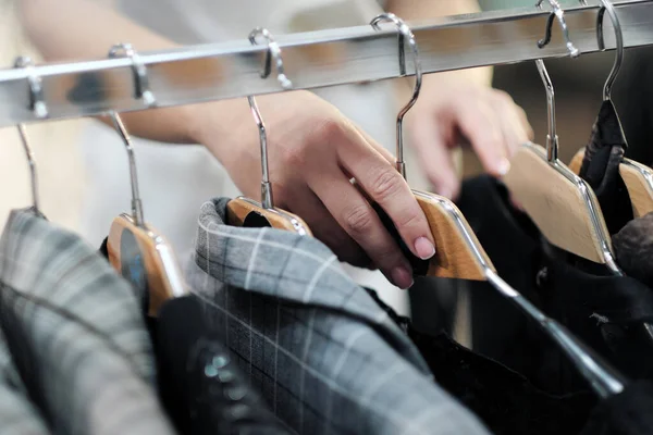 Zbliżenie rąk kobiety wybierającej ubrania na wieszaku w sklepie. — Zdjęcie stockowe