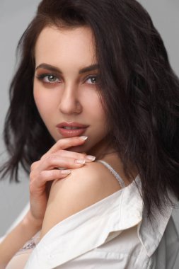 Güzel, kıvırcık, kahverengi saçlı, sütyenli, beyaz gömlekli ve kotlu kız..