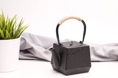 Beyaz zemin üzerinde siyah metal dökme demir çaydanlık.