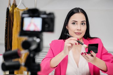 Pembe ceketli güzel bir kadın blogcu kozmetik hakkında bir blog çekiyor..
