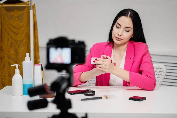 Krásná mladá žena blogger v růžové bundě střílí blog o kosmetice. — Stock fotografie