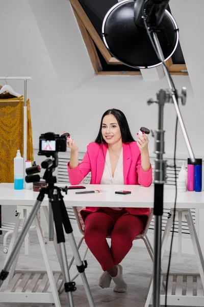 Ženské blogerky o kráse nahrávají video v bílé místnosti. Osvětlení a kamera na stativu. — Stock fotografie