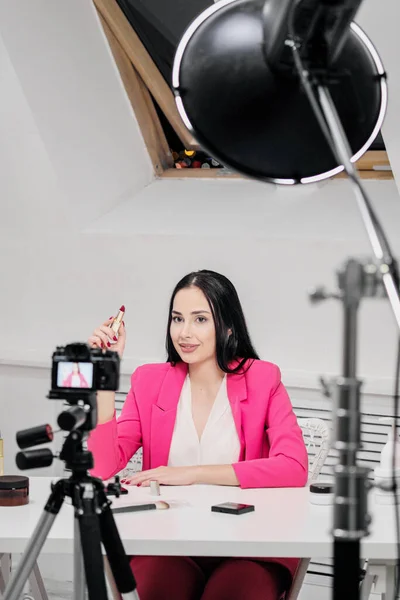 A female blogger online shoots a video about cosmetics. Shows and talks about lipstick.