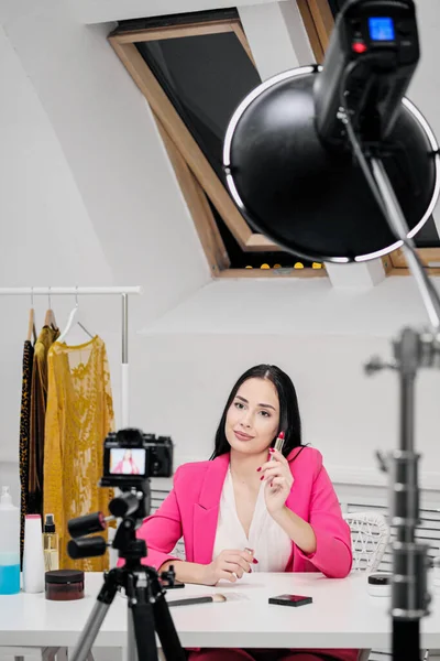 A female blogger online shoots a video about cosmetics. Shows and talks about lipstick.