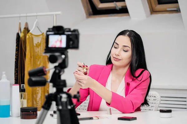 Ženské blogger on-line natáčí video o kosmetice. Zobrazuje a mluví o rtěnce. — Stock fotografie