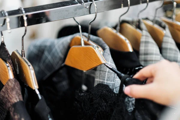Zbliżenie rąk kobiety wybierającej ubrania na wieszaku w sklepie. — Zdjęcie stockowe