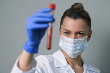 Kan testi. Kadın bir tıp çalışanı, üzerinde paciets kanı olan bir tüp tutuyor..