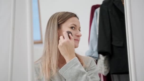 Egy fiatal, vonzó Y-generációs nő sminkeli magát otthon egy nagy tükörben.. — Stock videók
