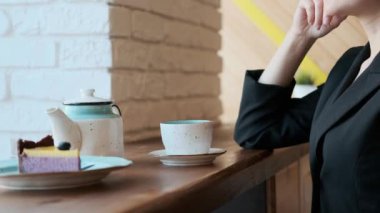 Gözlüklü genç çekici kadın pencerenin yanındaki kafede sıcak çay içiyor..