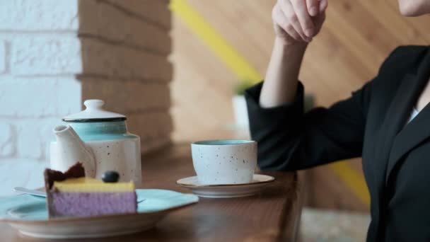 Jovem mulher atraente em copos bebe chá quente em uma mesa de café pela janela . — Vídeo de Stock
