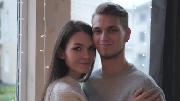 Retrato de una joven y hermosa pareja casada en casa sobre el fondo de una guirnalda y un árbol de Navidad . — Vídeo de stock