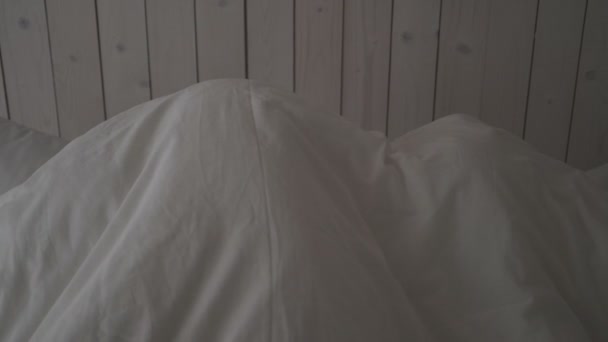 若い夫婦と男と女が寝室にいる。彼らはベッドの上で転がり、楽しみ、枕と抱擁を戦います。家族の夜. — ストック動画