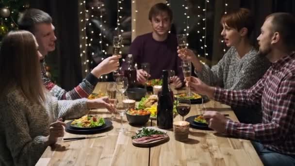 Amigos festa de férias jantar em casa em torno da mesa. Comemore o Natal. Cinco pessoas comem, bebem champanhe, falam e riem . — Vídeo de Stock