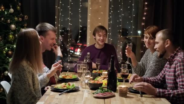 Baráti ünnepi vacsora otthon az asztal körül. Ünnepeljük a karácsonyt. Öt ember eszik, iszik pezsgőt, beszél és nevet.. — Stock videók