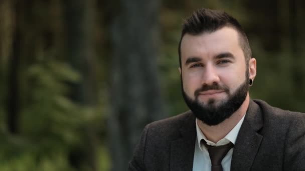 Closeup of a male businessman outdoors. Smiles and laughs. Attractive young man in a brown suit. — Stock Video