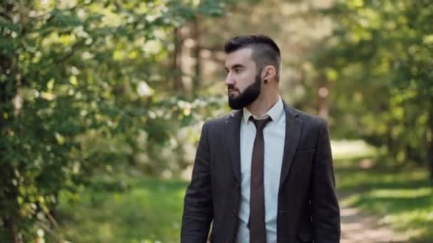 Primer plano de un hombre de negocios al aire libre. Sonrisas y risas. Joven atractivo en un traje marrón . — Vídeos de Stock