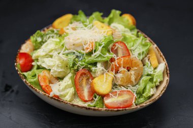 Siyah arka planda karidesli Sezar salatası.