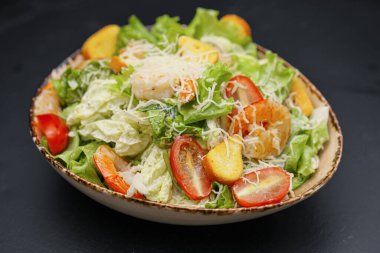 Siyah arka planda karidesli Sezar salatası.