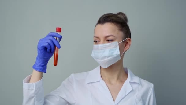 Teste de sangue. Uma médica do sexo feminino detém um tubo de ensaio com sangue de chupetas . — Vídeo de Stock