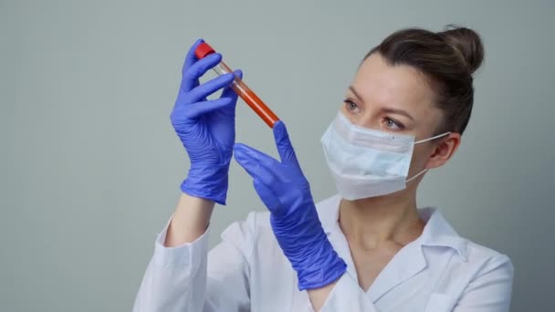 验血一名女医务工作者拿着一个装有软糖血的试管. — 图库视频影像