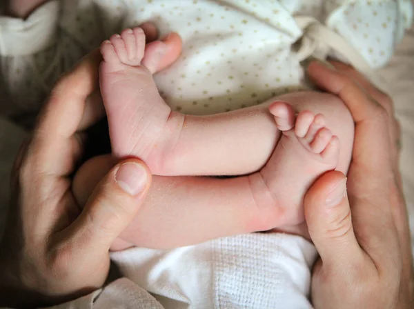 Les mains des hommes tenant des pieds de bébé nouveau-né — Photo