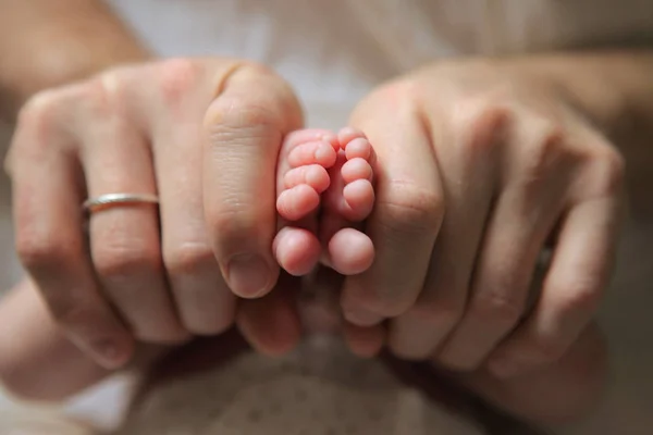 Les mains des hommes tenant des pieds de bébé nouveau-né — Photo