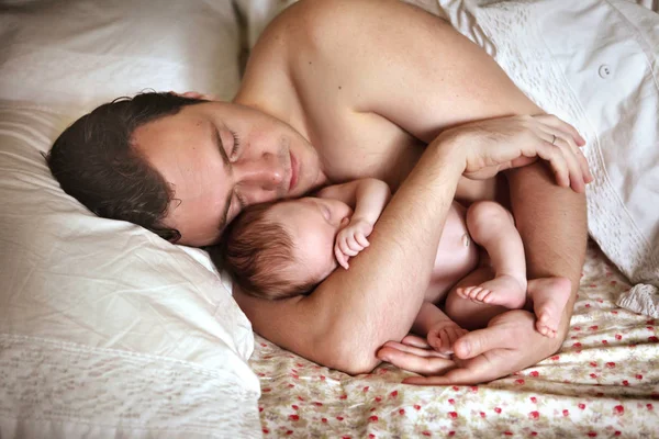 Ένας άνθρωπος με ένα μωρό στο κρεβάτι — Φωτογραφία Αρχείου