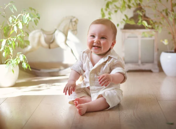 Oyuncaklar içinde belgili tanımlık geçmiş ile geniş bir ışık odada bir gömlek küçük bir çocuk oturur