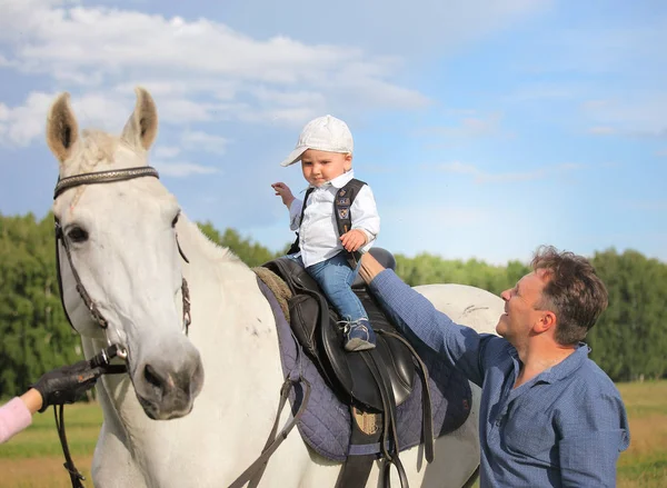 Reiten Vater mit seinem Sohn. Baby auf einem Pferd reiten. Papa bringt seinem Sohn bei, im Sattel zu sitzen. Baby mag ein Pferd — Stockfoto
