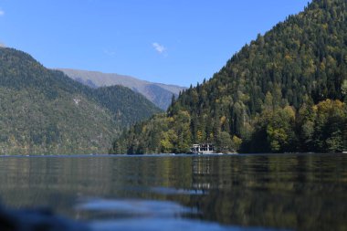 Bir dağ gölünün yüzeyinde uzanan dik orman dağları. Ve dağlarda da gökyüzü..