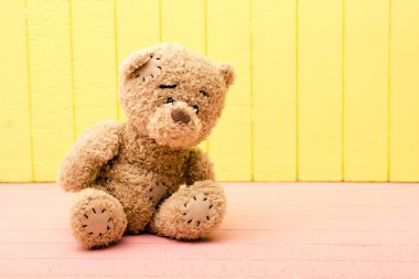 Oyuncak ayı oyuncak ahşap önünde sarı, pembe arka plan yalnız