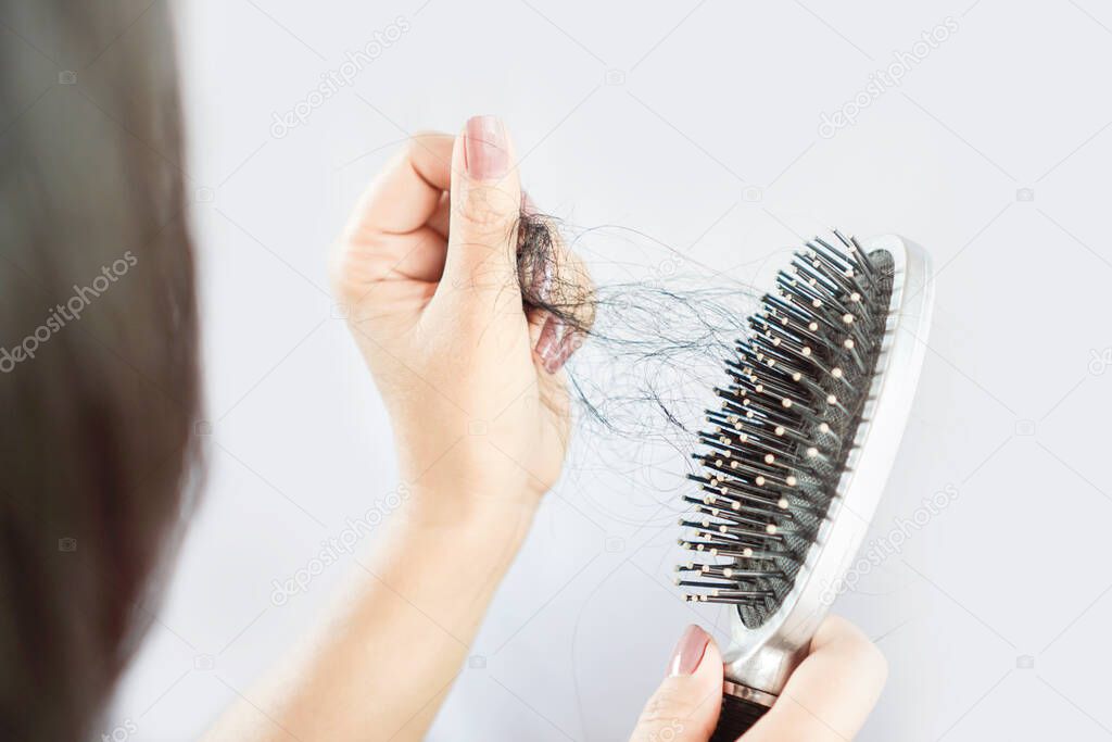 Asian woman hand holding hair loss falling on comb