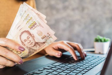 Kadın banknotları tutuyor ve bilgisayar kullanıyor, çevrimiçi para kazanıyor, kazanıyor, yatırım kavramı