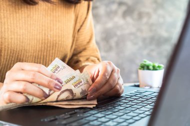 Kadın bilgisayarla banknotları sayıyor, çevrimiçi para kazanıyor, kazanıyor, yatırım yapıyor.