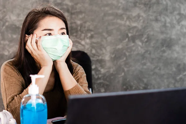 sad Asian woman worker sitting at home and wearing protective mask worry about covid-19 virus pandemic problem,thinking of losing her job