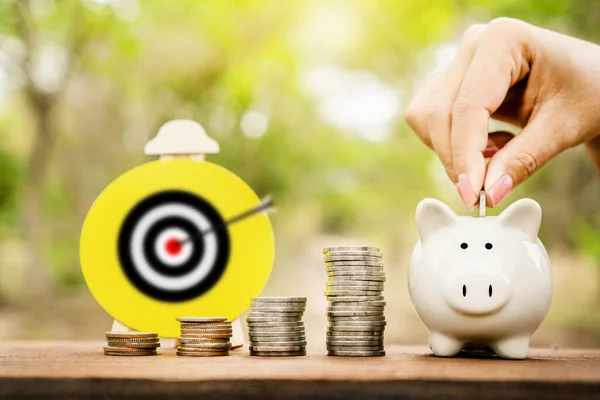saving money,retirement plan concept with hand putting coin in piggy bank and target in background